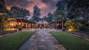 A spacious courtyard with a central open area, surrounded by lush greenery and a stone pathway. - Elewana Arusha Coffee Lodge (Arusha)