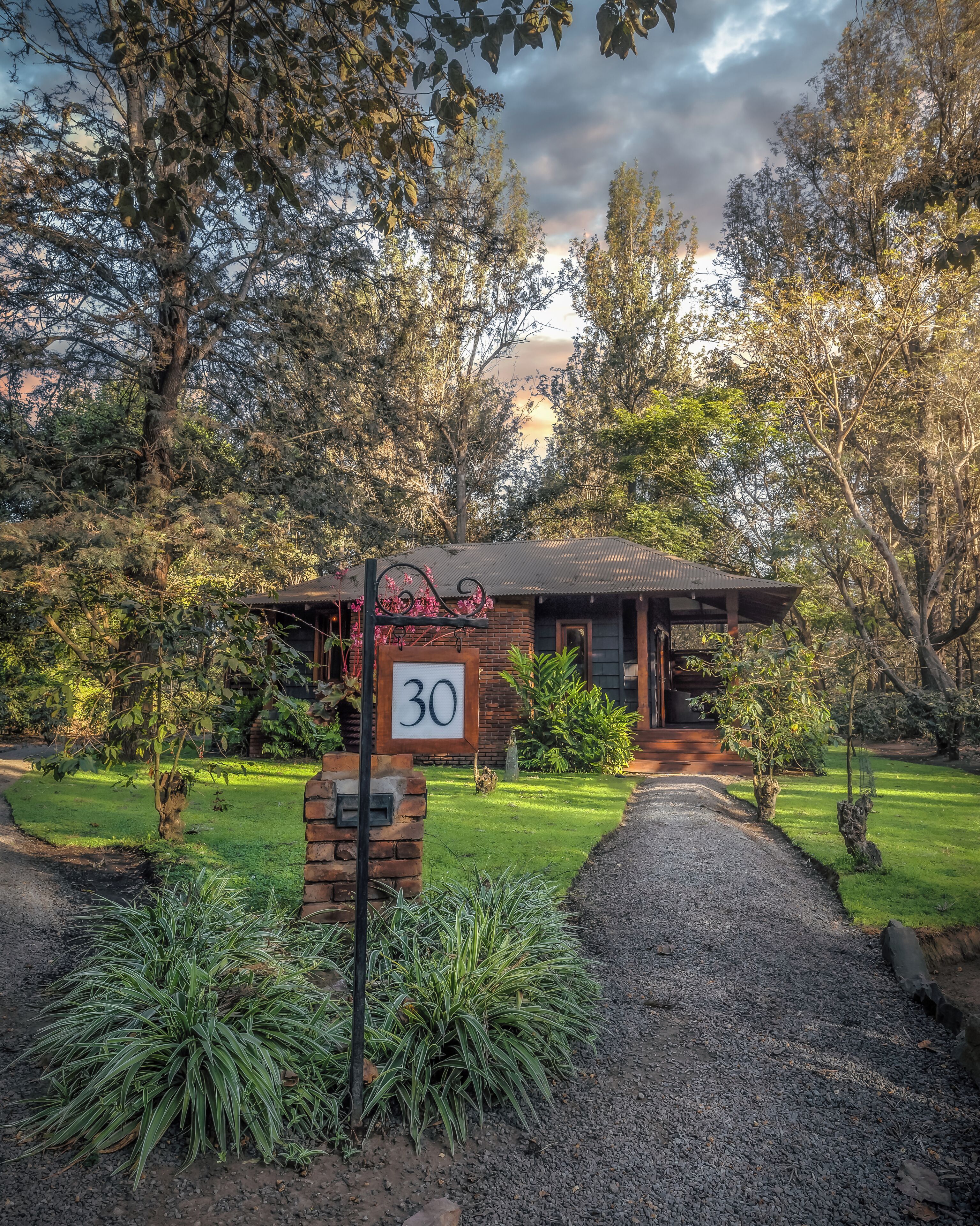 A house with a number sign, surrounded by trees and a well-maintained lawn.