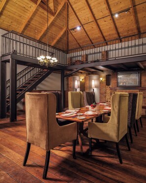 Comedor con techo alto, vigas a la vista y una escalera.