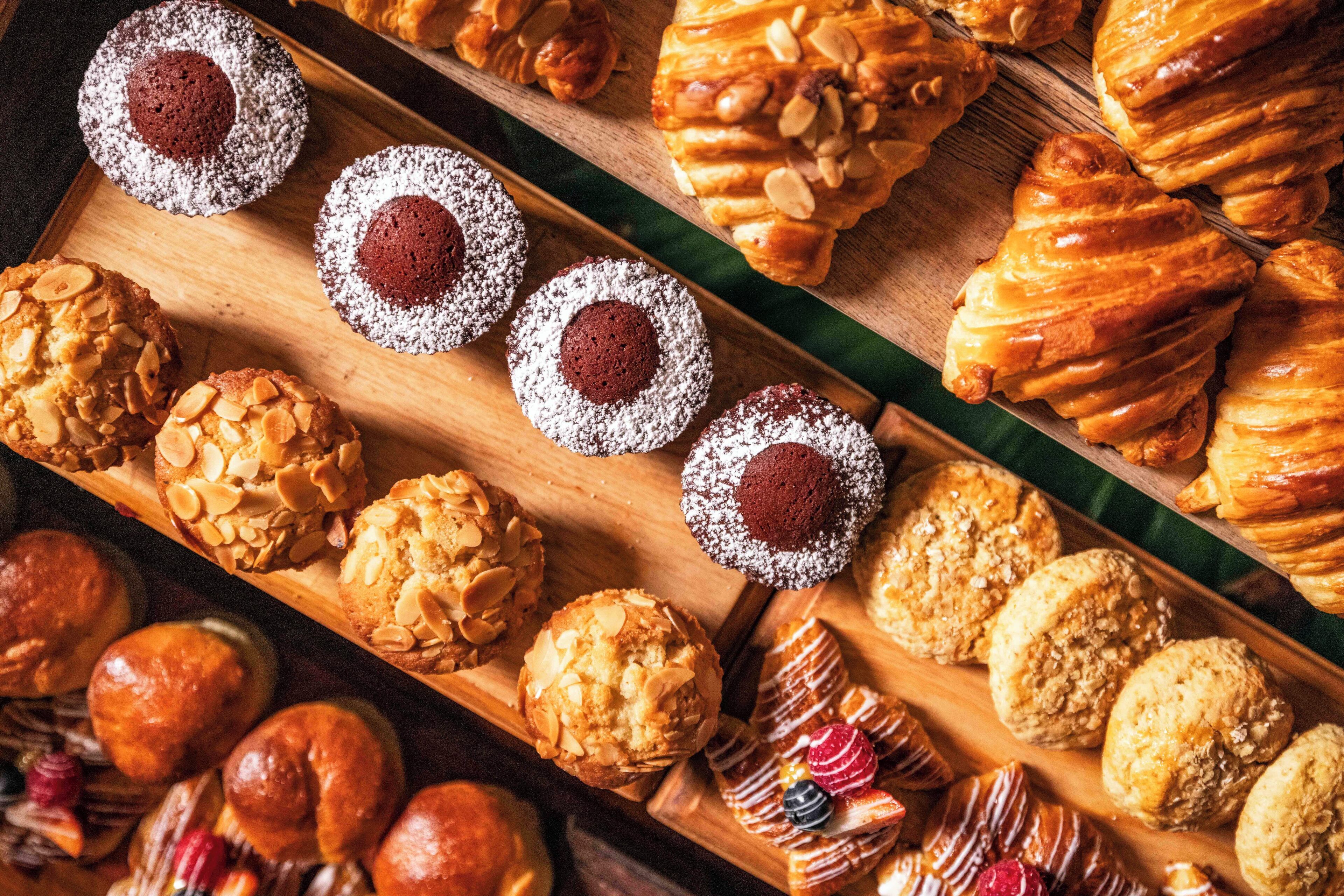 A variety of pastries and baked goods displayed on wooden trays.