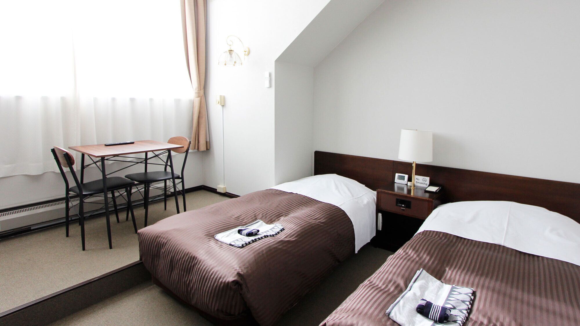 Ein Hotelzimmer mit zwei Betten, einem Schreibtisch und einem Stuhl.