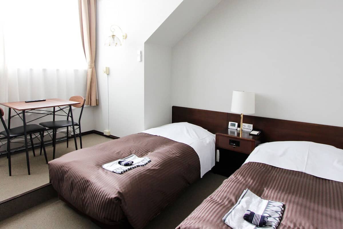 Habitación de hotel con dos camas, un escritorio y una silla.