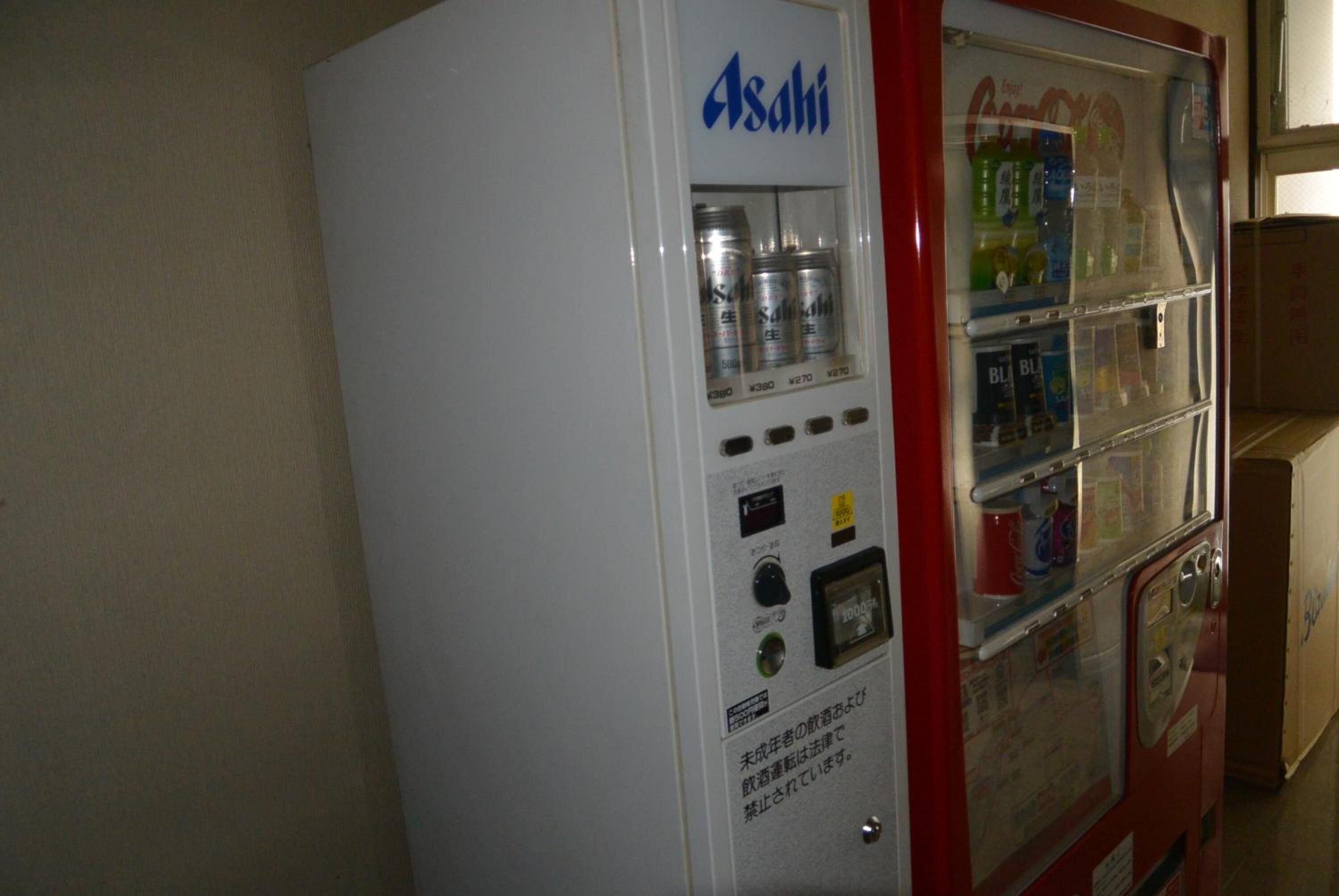 A vending machine with Asahi beer cans and a Coca-Cola machine.