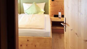 Ein Zimmer mit Holzboden, einem Bett, einem Nachttisch und einer Wandlampe.