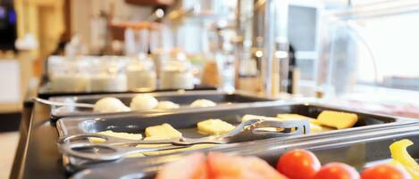 A buffet line with various food items including butter, cheese, and tomatoes.