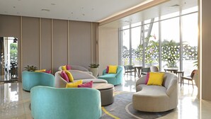 Een moderne lobby met zithoeken, grote ramen en kamerplanten.