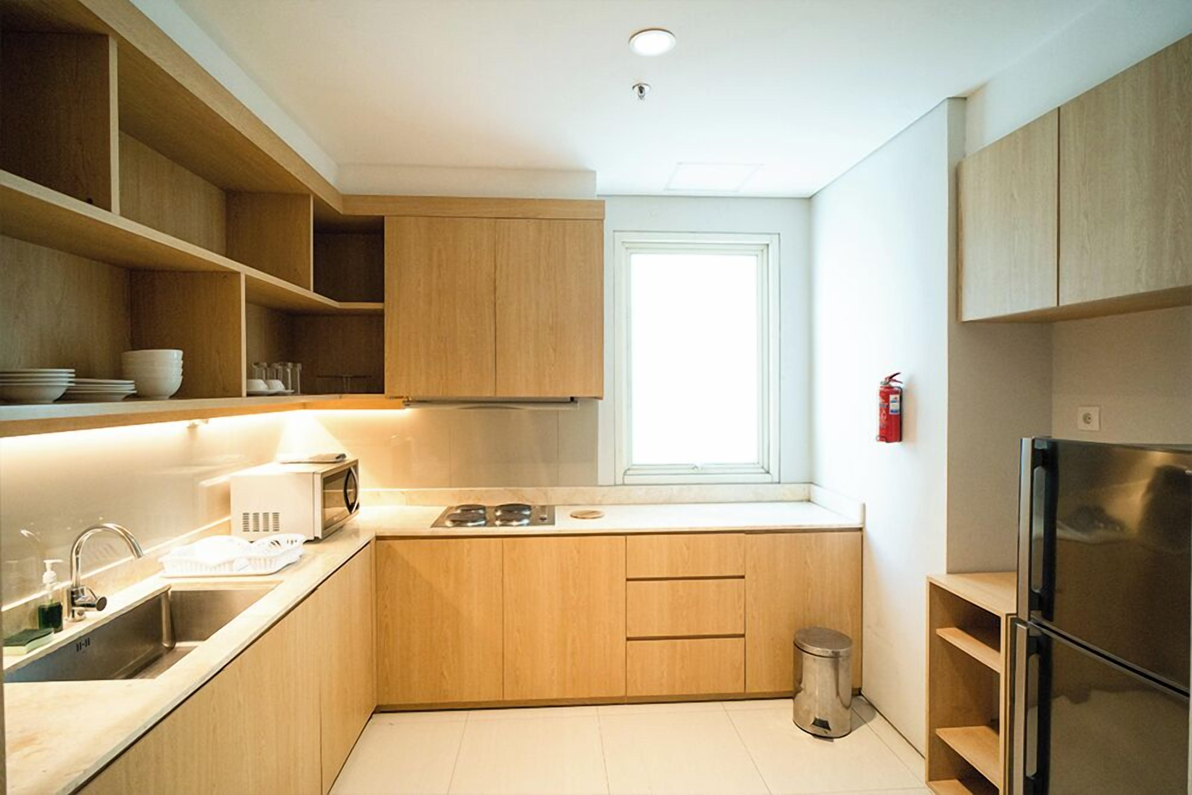 A modern kitchen with wooden cabinets, a stainless steel refrigerator, and a window providing natural light.