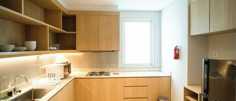 A modern kitchen with wooden cabinets, a stainless steel refrigerator, and a window providing natural light.