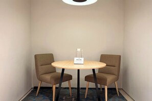 A small, round table with two chairs, a sign on the table, and a glass pitcher on the table. - Midtown Residence Surabaya (Surabaya)