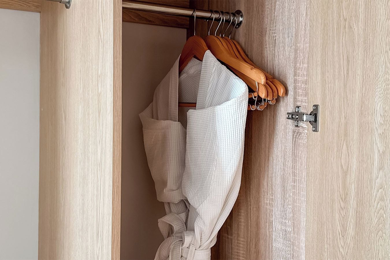 A wooden door with a metal latch and a wooden hanger with a white garment.