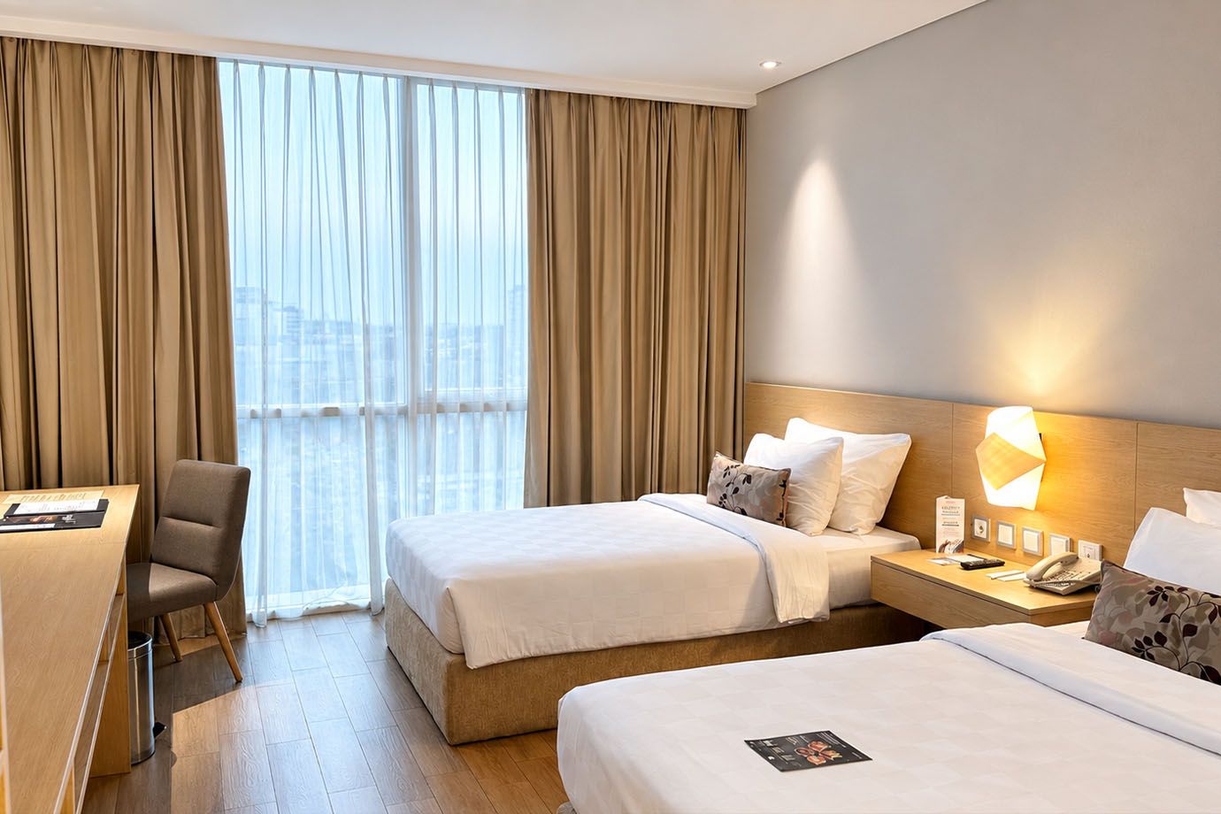 Ein Hotelzimmer mit zwei Betten, einem Schreibtisch und einem Stuhl.