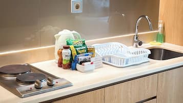A kitchen with a stainless steel sink, a faucet, a stove, and various food items on the counter.