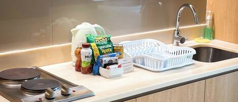 A kitchen with a stainless steel sink, a faucet, a stove, and various food items on the counter.