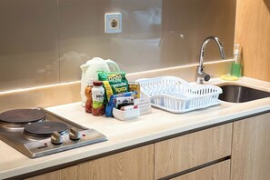 A kitchen with a stainless steel sink, a faucet, a stove, and various food items on the counter. - Midtown Residence Surabaya (Surabaya)