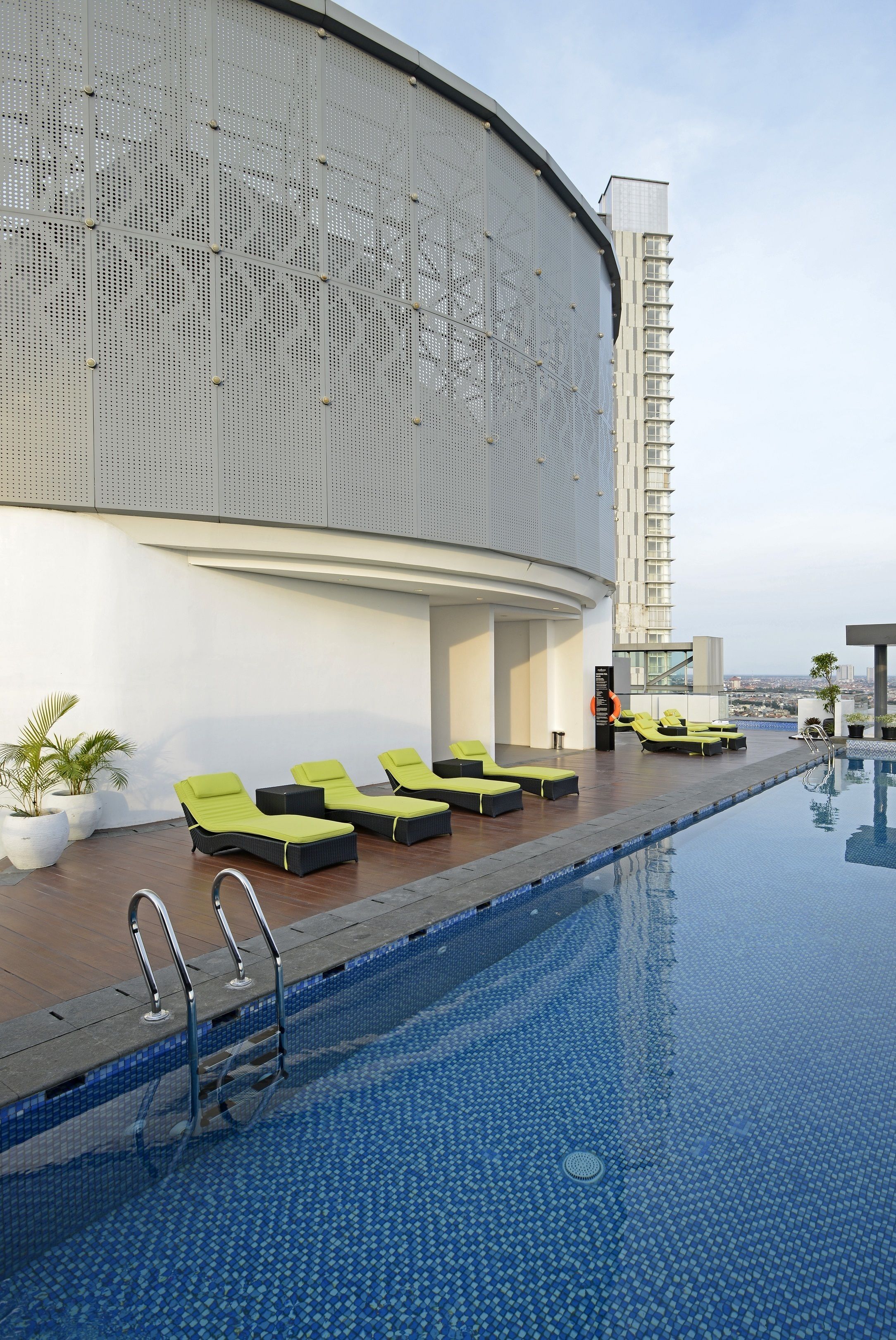 Un espace piscine aménagé sur le toit, avec des chaises longues et une vue sur le panorama urbain.
