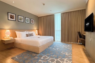 Una camera d'albergo con un letto grande, comodini, una televisione a schermo piatto e vista sulla città dalla finestra.