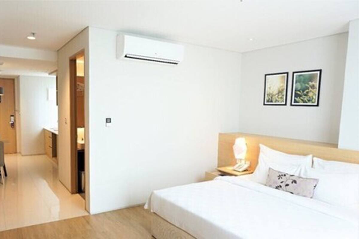 A hotel room with a bed, bedside table, lamp, and two framed pictures on the wall.