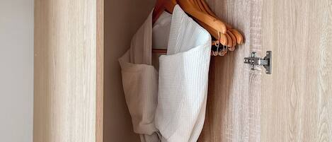 A wooden door with a metal latch and a wooden hanger with a white garment.