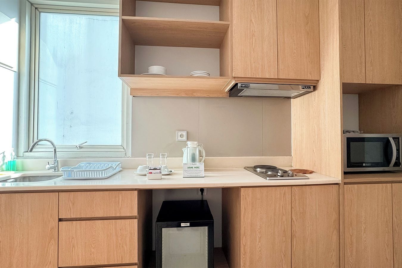 A compact kitchen with a microwave, sink, and storage cabinets.