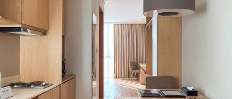 A modern kitchen with wooden cabinets, a built-in stove, and a dining area with a table and chairs.