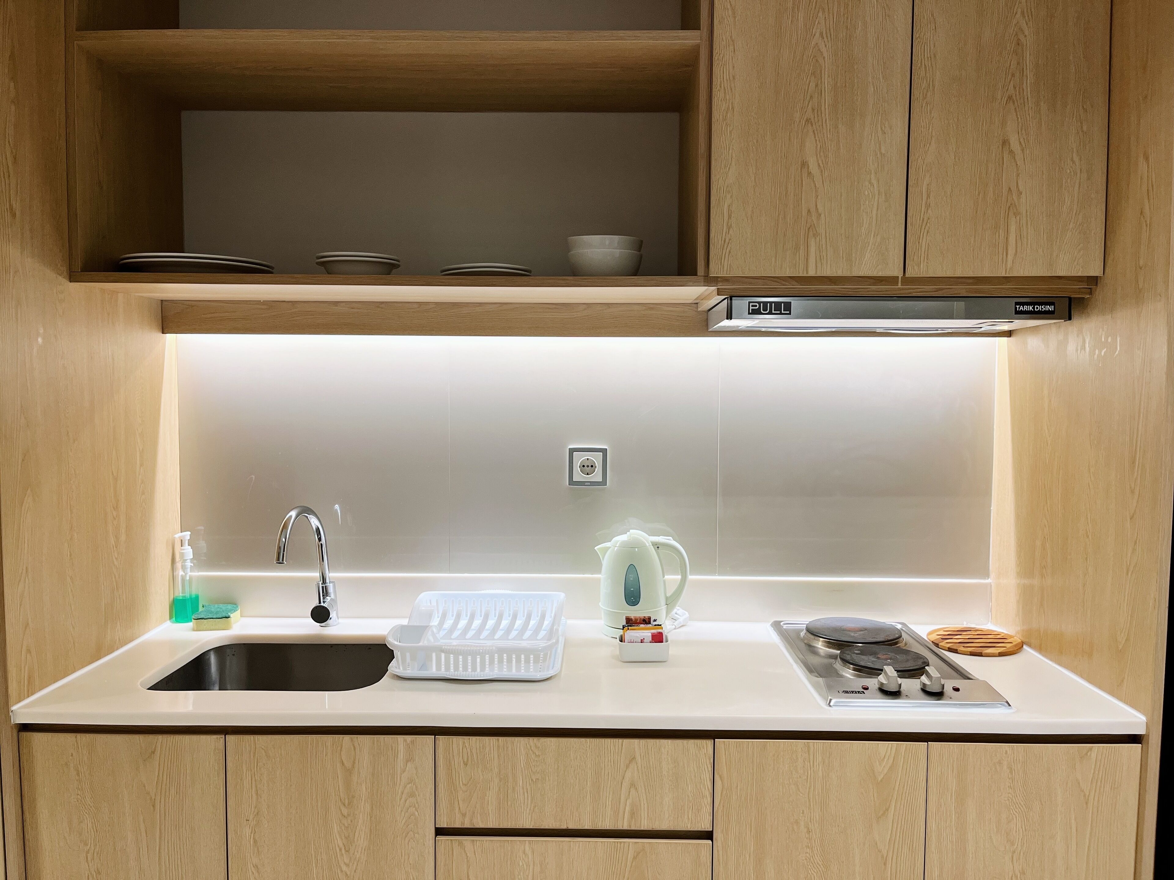 A modern kitchen with a stainless steel sink, a kettle, and a stove.