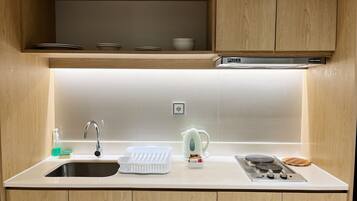 A modern kitchen with a stainless steel sink, a kettle, and a stove.