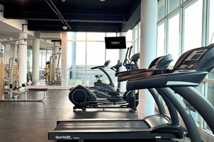A gym with cardio equipment, weight machines, and large windows.