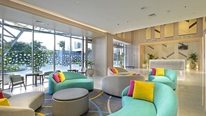 Een moderne lobby met zithoeken, grote ramen en een decoratieve wand.