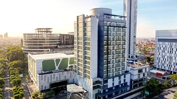 A modern hotel with a prominent cylindrical tower, a circular building with a green roof, and a rectangular building with a large glass facade.