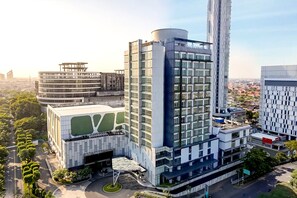 A modern hotel with a prominent cylindrical tower, a circular building with a green roof, and a rectangular building with a large glass facade. - Midtown Residence Surabaya (Surabaya)