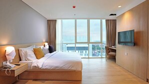 Een moderne hotelkamer met een groot bed, een televisie en uitzicht op de stad.