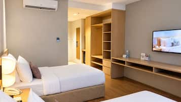 A hotel room with two beds, a TV, a bedside lamp, a phone, and a large wardrobe.