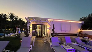 An outdoor lounge area with sun loungers and a covered seating area. - Skiathos Holiday Resort (Skiathos)