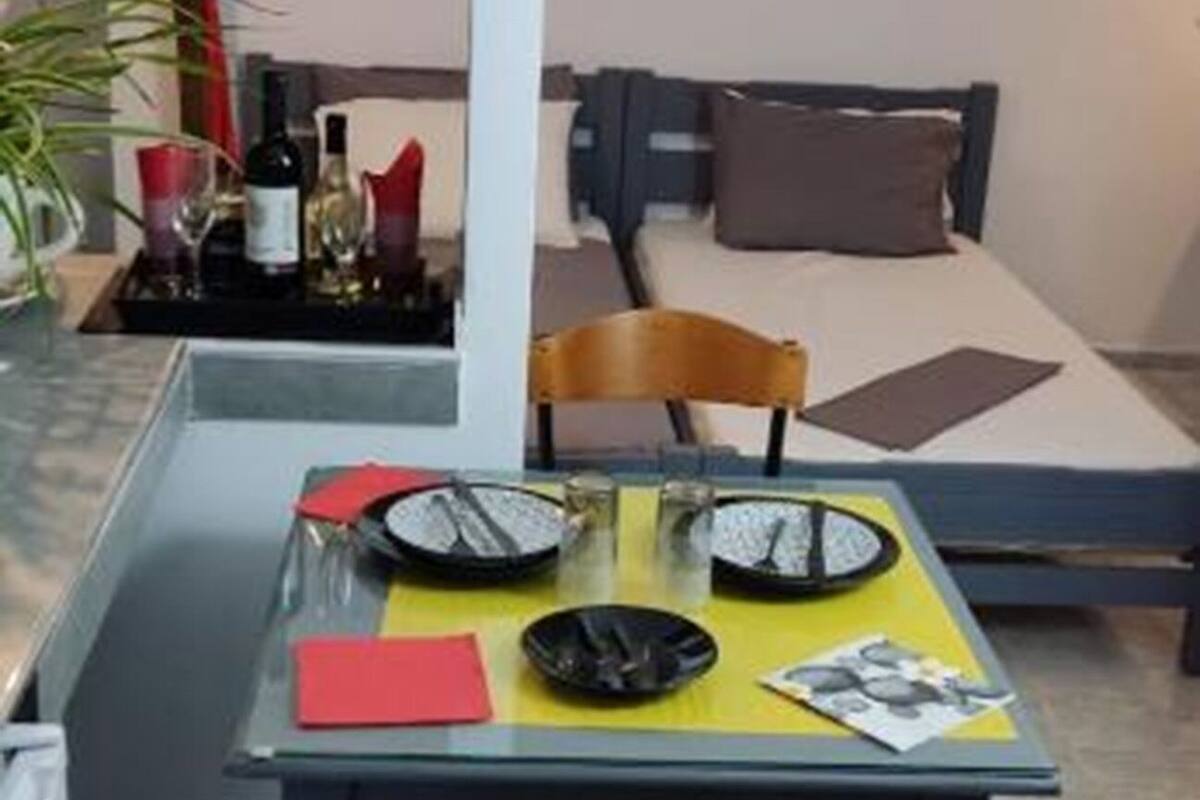 A compact living space with a dining area featuring a glass table, a chair, and a small kitchen area with a stove.