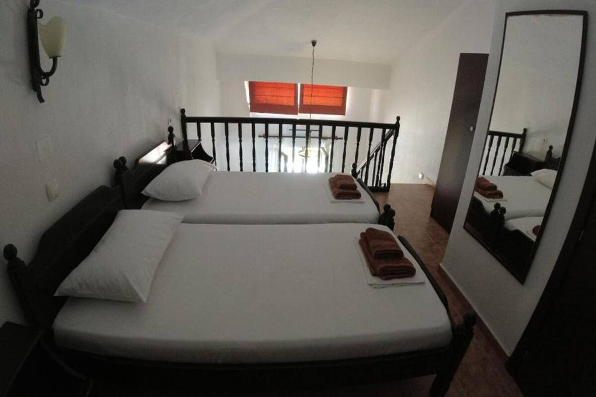 A room with two beds, a mirror, and a window with blinds.
