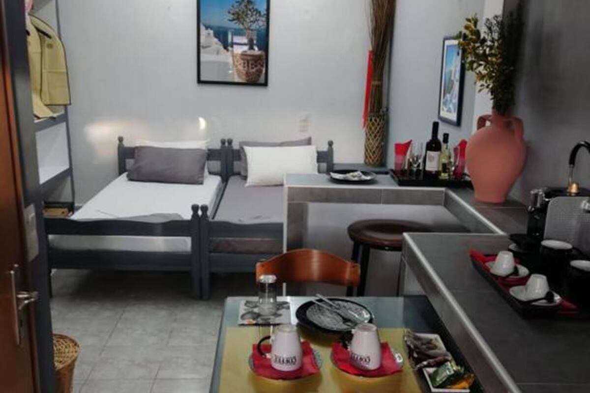 A modern hotel room with a bed, a small table with breakfast items, a mirror, and a painting on the wall.