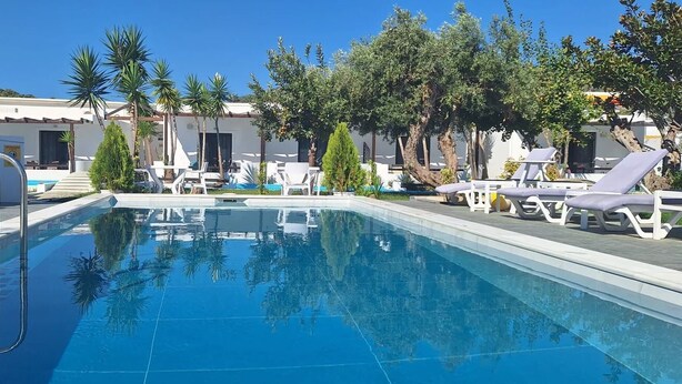 A swimming pool with lounge chairs and palm trees. - Skiathos Holiday Resort (Skiathos)