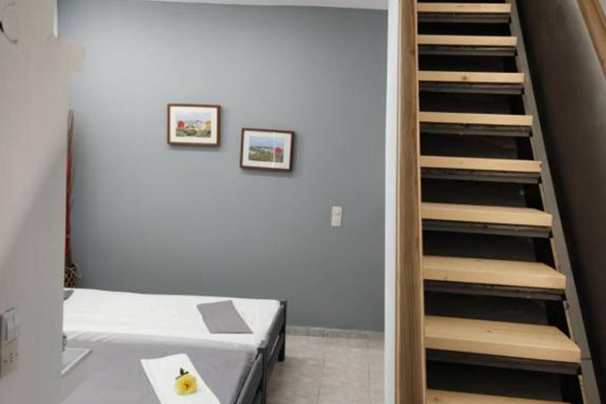 A bedroom with a bed, a small table, and a staircase.