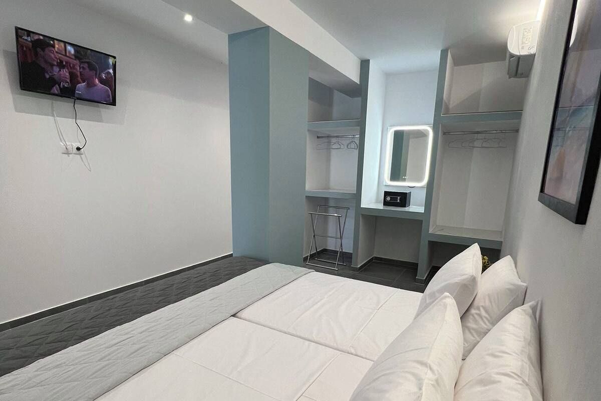 A modern hotel room with a large bed, a TV mounted on the wall, and a built-in wardrobe with a mirror.