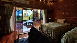 A wooden cabin room with a bed, a chair, and a table. - Nagahama Beach Resort Kanon (Nakijin)