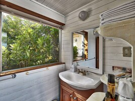 Une salle de bain avec une fenêtre, un lavabo et un miroir.