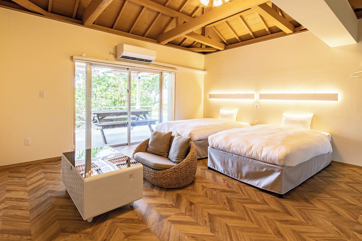 Een kamer met twee bedden, een plafondventilator en uitzicht op een terras.