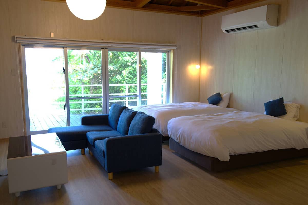 A bedroom with two beds, a sofa, and a small table.