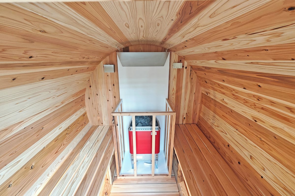 A wooden interior with a central staircase leading to a red bench.