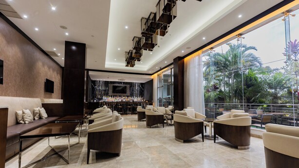 A modern lounge area with a bar, seating arrangements, and a view of greenery through large windows. - Crowne Plaza Nairobi Airport by IHG (Nairobi)