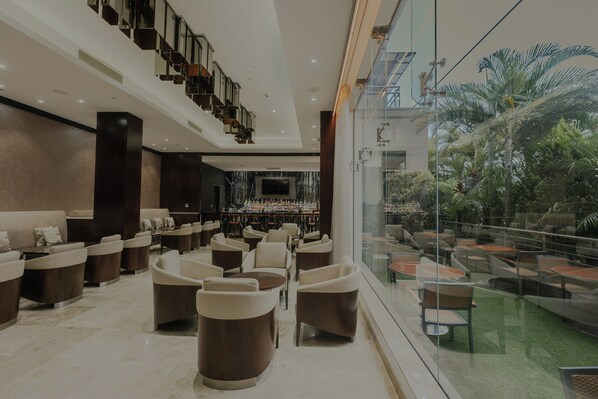 Un vestíbulo amplio con zona de bar, asientos cómodos y vistas al exterior.