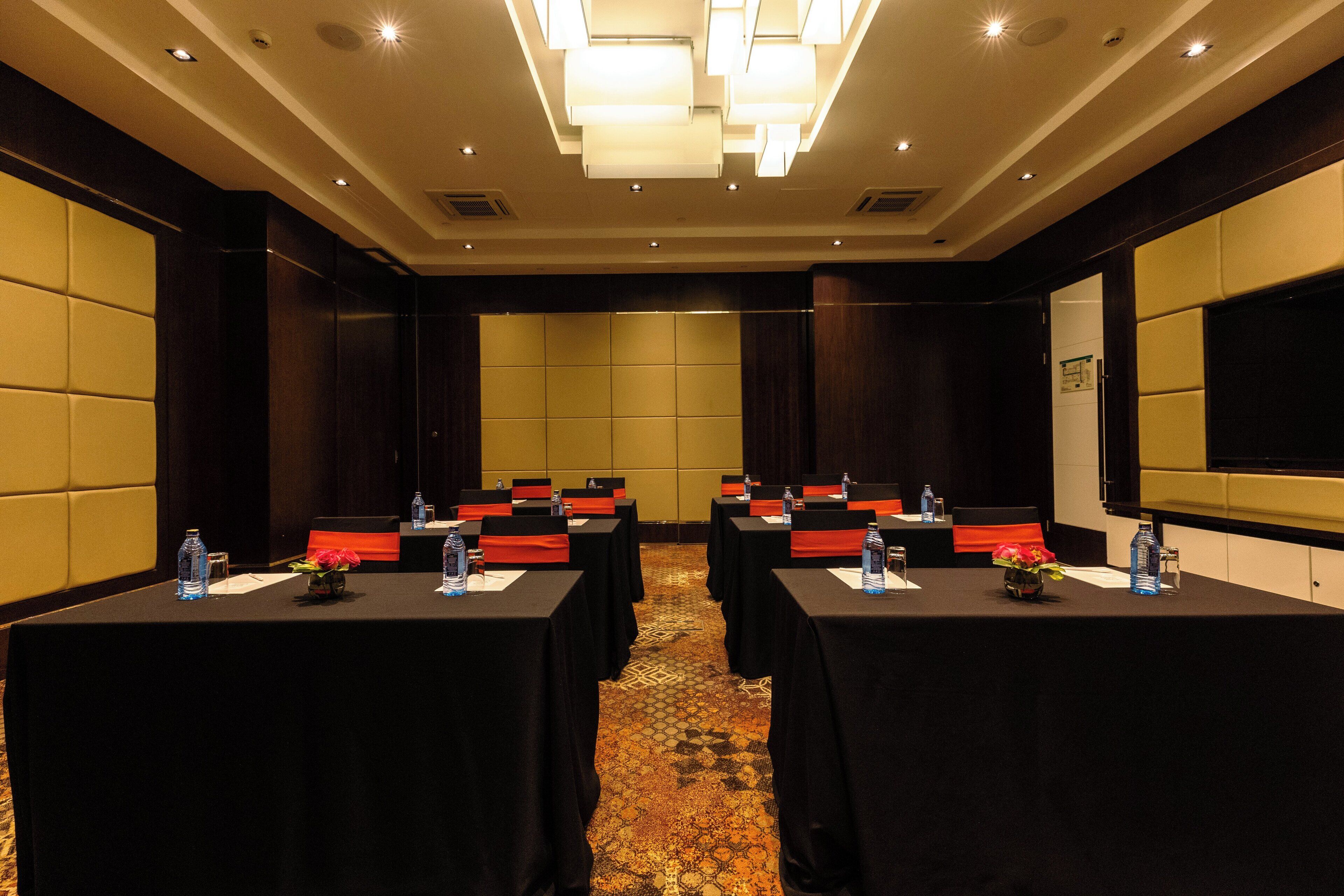 A conference room with tables, chairs, and a projector screen.