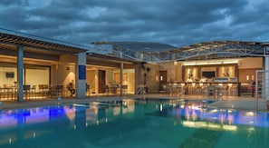 Une piscine intérieure avec un bar et des espaces pour s’asseoir.
