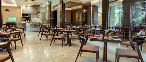 A spacious restaurant with high ceilings, modern pendant lighting, and a clean, polished floor.