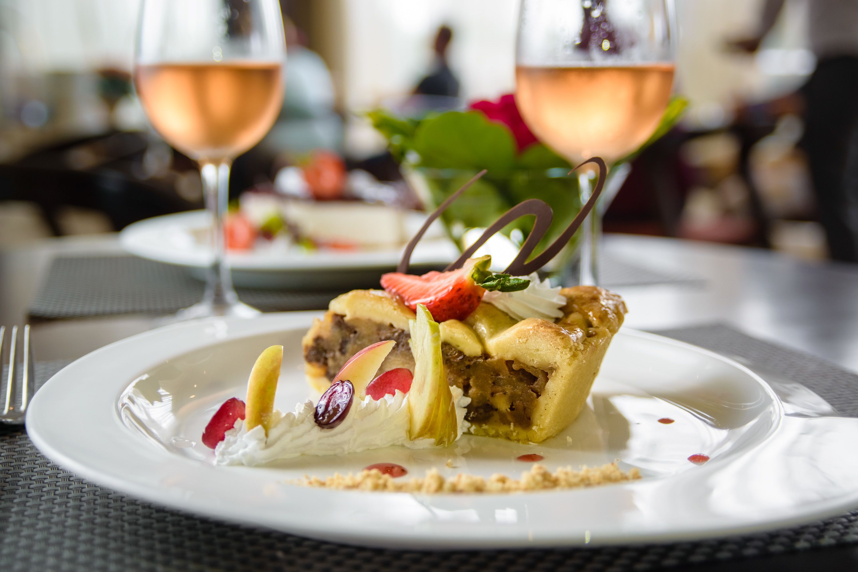 A dessert on a plate with a glass of wine in the background.